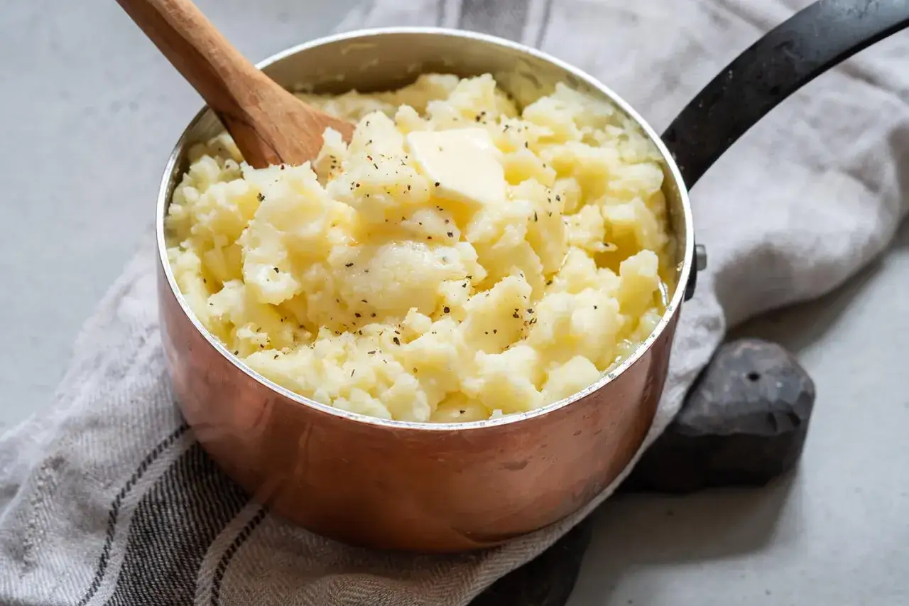 Cremiger Kartoffelbrei im Kupfertopf, garniert mit Butter und Pfeffer. Ein einfaches Kartoffelbrei Rezept für jeden Tag.