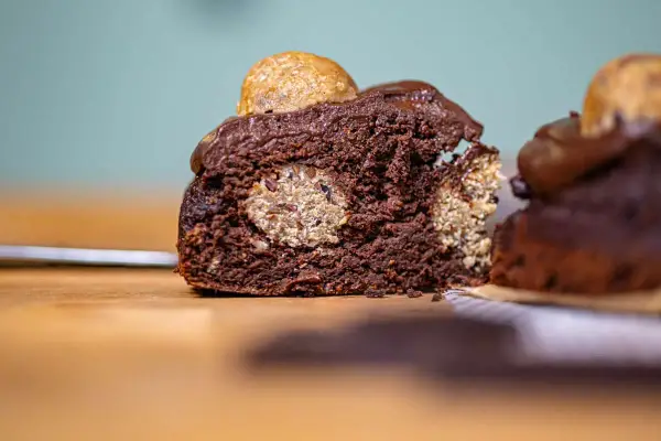 Saftiger Schokoladenkuchen mit versteckten Cookie Dough Kugeln und einem Topping aus Schokoladenglasur und einer weiteren Cookie Dough Kugel.
