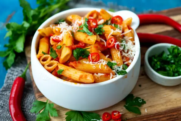 Eine Schüssel Penne all'Arrabbiata, garniert mit frischer Petersilie und Chilischeiben.